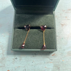 Guldörhängen med röda hjärtformade stenar från Maria Nilsdotter - Säljer ett par eleganta örhängen i guld platering med hjärtformade röda stenar och hängande droppformade röda stenar. Dem är från Maria Nilsdotter och jag gjorde nyligen om plateringen på dem! Pris kan diskuteras men skriv om ni har någon fundering!