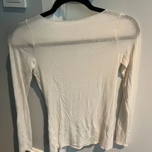 Vit intimissimi topp - Säljer en tunn och stilren vit långärmad topp från intimissimi. Toppen har en rund halsringning och är tillverkad i ett mjukt och lätt material som passar perfekt till lager-på-lager eller som basplagg. Den är inte lika genomskinlig som den ser ut på bilden! Skicka gärna till mig vid vidare frågor😊🫶🩷