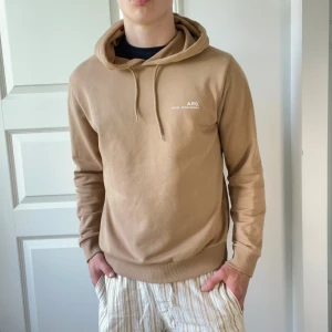 Apc hoodie  - Väldigt bra skick som ny! Beige Apc hoodie. Modellen bär M och är 178 cm 74 kg. 