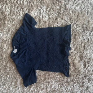 Mörkblå topp med volang från Gina Tricot - Säljer en mörkblå topp från Gina Tricot i storlek 158/164. Toppen har korta ärmar, smockat parti framtill och volangdetalj nedtill. Perfekt för dig som gillar en söt och stilren look. Använd fåtal gånger🤍 Som ny och pris går att diskutera🤍