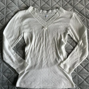 Vit långärmad topp med spets - Söt vit långärmad topp med v-ringning och spetsdetaljer.