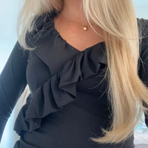 Svart figurnära topp med volang  - Jättefin svart topp i storlek xs med volang, toppen är figurnära och har ett stretchigt material som sitter snyggt på kroppen, den är i mycket bra skick utan några skador. Toppen finns även inte att köpa ny längre💕