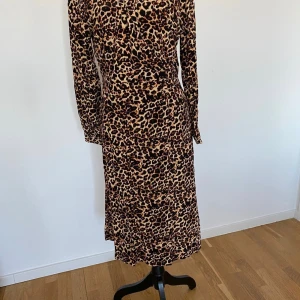 Helt ny klänning från M&Q i strl M, med prislapp - Helt ny klänning med prislapp.  Nypris 699kr. Långärmad klänning från Visual Clothing Project med omlottliv och klädda knappar. 