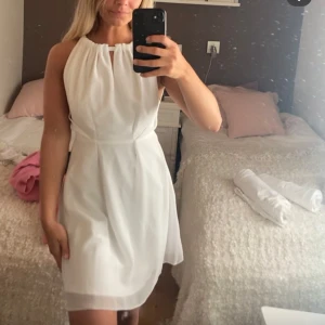 Vit kortklänning från Zetterberg Couture - Säljer en stilren vit kortklänning från Zetterberg Couture. Klänningen har en halterneck-ringning med liten öppning framtill och markerad midja. Perfekt för student eller sommarens festligheter. Tunn, lätt och elegant design.nypris  2599. Den är i storlek 36 men lite insydd i midjan☺️skriv för fler bilder:) de är dragkedja baktill samtlnytning