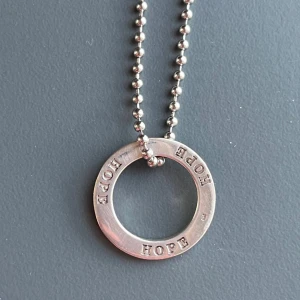 Nytt HOPE-halsband från Lois Lane i äkta 925  silver 925 – Pris i butik 400 kr -  Oanvänt halsband från Lois Lane med rund berlock i äkta stämplat silver (925), ingraverad med “HOPE” hela vägen runt. Kedjan är ca 42 cm och i nickelsäkert stål. Ringen mäter ca 2 cm i diameter. Nypris ca 400 kr – här får du ett stilrent och symboliskt smycke till fyndpris. Ingen prutning – men jag erbjuder Bundlerabatt vid köp av flera varor. 