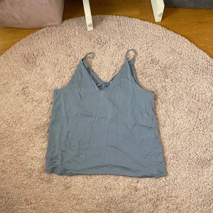 Ljusblå linnetopp från H&M - Säljer en ljusblå linnetopp från H&M med smala axelband och v-ringning. Toppen är enkel och stilren, perfekt att matcha med jeans eller kjol. Materialet känns mjukt och lätt mot huden.