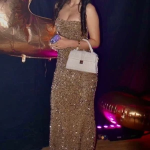 Glittrig guldig långklänning med paljetter - Säljer en glittrig guldig långklänning med paljetter . använts en gång, off shoulder💗