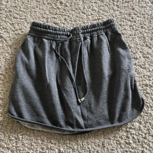 Grå mjukiskjol från Bik Bok Balance - Mysig grå mjukiskjol från Bik Bok Balance med elastisk midja och dragsko. Kjolen har sidofickor och är perfekta för en avslappnad stil. Tillverkad i mjukt material som känns skönt mot huden.