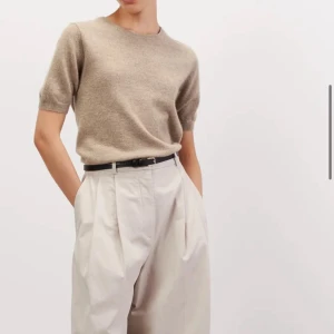 Soft Goat Beige stickad kortärmad tröja från Soft Goat  - Säljer en stilren beige stickad tröja från Soft Goat med korta ärmar och rund halsringning. Tröjan har en mjuk och lyxig känsla, perfekt att matcha med både jeans och kostymbyxor. Kvitto finns