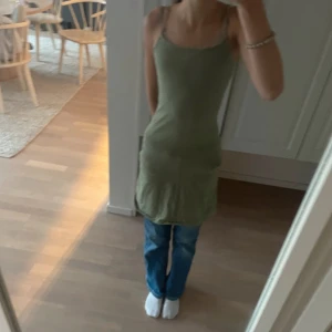 Grön tight klänning från H&M - Säljer en enkel och stilren lite mörkare grön klänning från H&M med smala axelband och tight passform. Klänningen är ärmlös och gjord i mjuk bomull, perfekt för varma dagar eller att styla, jeans är på under, inget man behöver ha . 