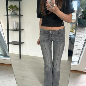 Grå lågmidjade bootcut jeans från Gina - Skitsnygga grå jeans med bootcut passform och markerade sömmar. Byxorna har stora fickor framtill och klassisk knapp- och dragkedjestängning. Perfekta för både skola och fest😍