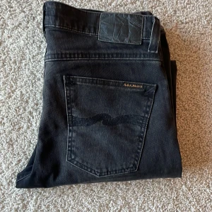 Svarta Nudie Jeans Lean Dean - Svarta nudie jeans i storlek 30/32. Modellen är Lean Dean. De är i mycket bra skick, inga defekter och har ändast använts ett fåtal gånger. Säljer då de har blivit för små för mig. Skriv vid minsta funderingar om mått eller liknande.