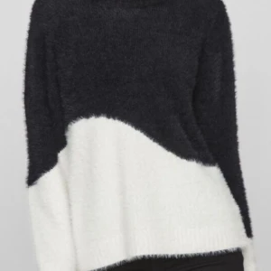 Svart och vit fluffig tröja - Mysig och fluffig tröja i svart och vitt med asymmetrisk stil. Tröjan har långa ärmar och en lös passform som ger en avslappnad stil. Bra skick!!🙌🏻🙌🏻💖Passar även XS och S