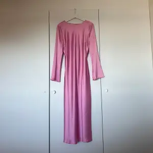 Elegant rosa långklänning med långa ärmar och en vacker detalj där bak där man kan knyta. Klänningen har en mjuk och glansig yta som ger en lyxig känsla. Den är helt ny så är i väldigt bra skick och lappen sitter fortfarande kvar. Den är i storlek L men skulle mer säga att den är om en M då materialet inte är så stretchigt🫧🤍💕