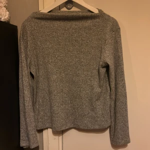 Grå stickad tröja - Säljer en mysig grå stickad tröja med långärmad design. Perfekt passform och enkel att matcha med olika outfits. Tröjan har en klassisk stil och är bekväm att bära.