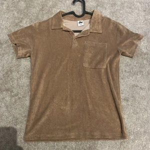 Brun frotté t-shirt med krage - Säljer en brun kortärmad frotté piké,Storlek 158/164