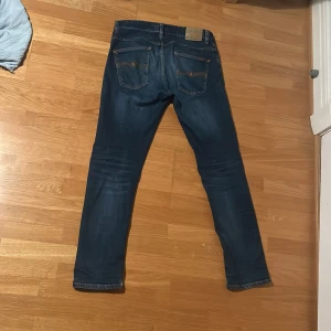 Nudie Grim Tims - Säljer ett par snygga blå jeans. De har en klassisk femficksdesign och en knappgylf. Köpta för 1600.