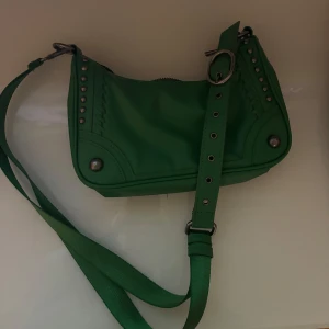 Grön axelväska med nitar - Snygg grön axelväska med justerbar axelrem och nitar som detaljer, från Zara! Perfekt för att ge din outfit en edgy touch. Väskan har en praktisk storlek för vardagsbruk.
