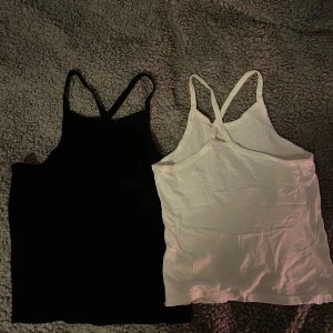 Svart och vit topp - Två stilrena linnetoppar i svart och vitt. Perfekta för varma dagar eller som lager under andra plagg. De har smala axelband och en enkel design som gör dem lätta att matcha med olika outfits.