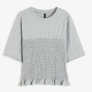 Grå smockad topp från hm  - Säljer denna populära och slutsålda hm tröja. Den är aldrig använd och prislappen är kvar. Perfekt både till vardags och fest. Den är i storlek s men passar även xs och m beroende på hur man vill att den ska sitta💗