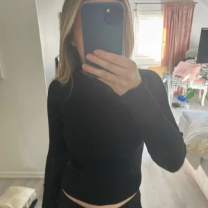 Svart långärmad topp med öppen rygg - Snygg svart långärmad topp med en stilren öppen ryggdetalj. Perfekt för en trendig look. Passar bra till både jeans och kjol. Använd en gång 