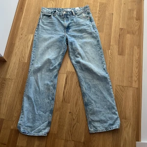Ljusa jeans med nitar - Säljer ett par ljusa jeans med coola nitar på bakfickan och vid bältesslingorna. De har en loose passform och är perfekta för en avslappnad stil. Jeansen har en klassisk femficksdesign och är tillverkade i denim.