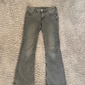 Grå bootcut jeans - Snygga grå bootcut jeans med klassisk femficksdesign och knappgylf. Perfekta för en avslappnad stil med en touch av retro. Passar bra till både sneakers och klackar.