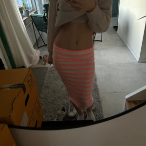 Rosa och vit randig kjol - Säljer en snygg rosa och vit randig kjol med en tight passform. Kjolen är midilång och perfekt för sommarens varma dagar. Den har en elastisk midja för extra komfort, är egentligen i storlek M men passar även mig som har storlek S. Passar perfekt till en enkel topp eller blus. Pris kan diskuteras💘