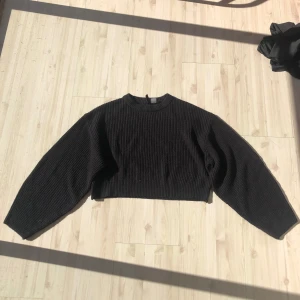 Svart croppad tröja - Säljer en svart ribbad croppad tröja med långa ärmar. Perfekt för en stilren och modern look. Tröjan har en enkel design som passar till många olika outfits.