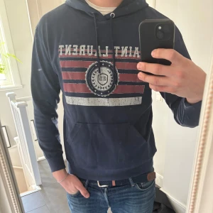 Saint Laurent Hoodie - Säljer en snygg mörkblå hoodie från Saint Laurent med ett eftertraktat tryck. Hoodien är i bra skick och i storlek L. Tveka inte på att höra av er för flera bilder!