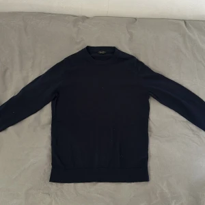 Marinblå tröja från Massimo Dutti - Säljer en stilren marinblå tröja från Massimo Dutti. Tröjan är tillverkad i merinoull och har en klassisk design med långa ärmar och rund hals. Perfekt för en elegant och avslappnad look. Storlek M men passar S