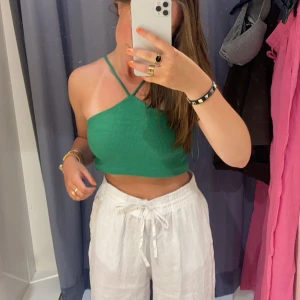 Grön croppad linnetopp - Snygg grön croppad linnetopp med smala axelband. Perfekt grön nyans, endast använd en gång, så otroligt bra skick, säljer för den inte kommer till användning. På bilden har jag vikt upp den lite, men kan ha den så den täcker ner till naveln med.