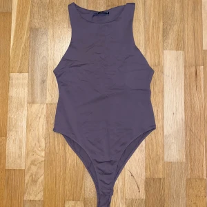 Brun ärmlös bodysuit från Zara - Säljer en stilren brun ärmlös bodysuit från Zara. Perfekt för lager-på-lager eller att bära som den är. Tillverkad i ett mjukt och stretchigt material för en  passform.
