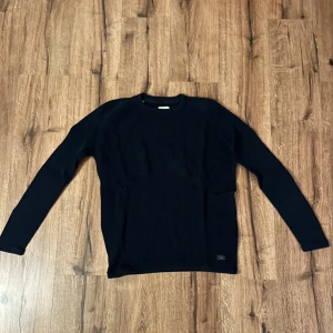 Mörkblå ribbad tröja från Selected Homme - Säljer en stilren mörkblå ribbad tröja från Selected Homme. Tröjan har långa ärmar och en klassisk rund halsringning. Perfekt för en avslappnad men ändå snygg look. Passar bra till både jeans och chinos.