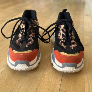 Svarta sneakers med leopardmönster - Snygga svarta sneakers med leopardmönster och röda detaljer. Skorna har en chunky sula i vitt och grått samt snörning framtill. Säljer för att jag numer har stl 39. Hämtas på Söder el fraktas