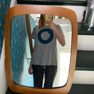 Grå t-shirt med tryck - Säljer en grå t-shirt med ett stort grönt och blått cirkeltryck på framsidan. T-shirten har en avslappnad passform och korta ärmar. Materialet är mjukt och bekvämt. Trycket är tyg sytt till mönstret i blått och grönt. Vid frågor hör gärna av er. Står som M men jag är Xs och fungerar också