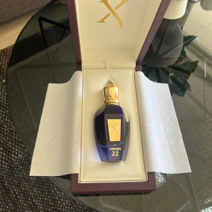 Xerjoff Torino 22 Parfym - Lyxig parfym från Xerjoff i en elegant mörkblå flaska med gulddetaljer. Kommer i en exklusiv vinröd förpackning med gyllene logotyp. Perfekt för den som söker en sofistikerad doftupplevelse. Köpte de i september förra året men eftersom att det är en sommar parfym så har kanske 2 ml använts. Säljer nu eftersom att jag behöver pengar till andra grejer. 