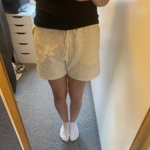 Grå bomullsshorts med snörning - Säljer ett par bekväma grå shorts i bomull med elastisk midja och snörning. Perfekta för en avslappnad dag hemma eller ute. De har en loose passform som ger en skön känsla.