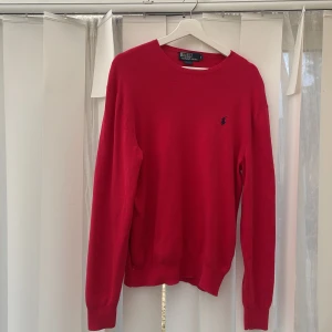 Röd tröja från Polo Ralph Lauren - Säljer en stilren röd tröja från Polo Ralph Lauren med det klassiska logotypbroderiet på bröstet. Tröjan har en slim fit passform och är långärmad, perfekt för en snygg och avslappnad look.