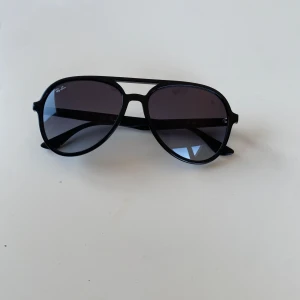 Svarta ”pilotglasögon” från Ray-Ban (solgalsögon) - Snygga svarta pilotglasögon från Ray-Ban med klassisk design. De har en svart ram och mörka linser som ger ett stilrent intryck. Perfekta för soliga dagar och kommer med ett brunt fodral för säker förvaring. Använda 1 gång.