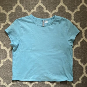 Ljusblå t-shirt från H&M Divided - Säljer denna ljusblå t-shirt från H&M Divided eftersom att den inte kommer till någon användning. Nästan som ny då den bara ha använts ett fåtal gånger🥰