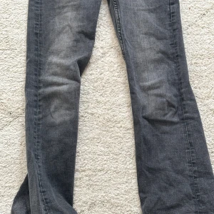 Svarta jeans med bootcut - Snygga svarta jeans med bootcut och låg midja. De har två knappar fram och fickor med knappdetaljer bak. Perfekta för en avslappnad stil. Man kan anpassa med knapparna vid midjan så den sitter perfekt. Storlek 146-152