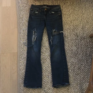 Mörkblå slitna jeans från LTB - Mörkblå jeans från LTB med tydliga slitningar och hål på båda benen framtill. Klassisk femficksmodell med bruna sömmar och knappgylf. Modellen heter Valerie och är inte helt raka ner till utan mer åt bootcut hållet skulle jag säga. Har inga bilder med dom på då dom är för små på mig men kan lova att dom är väldigt snygga!