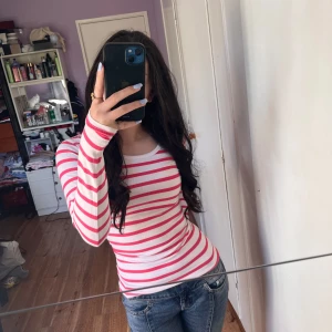 Randig långärmad tröja från Cubus - Säljer en vit och rosa långärmad tröja från Cubus. Tröjan har ett klassiskt randigt mönster och är figurnära i passformen. Perfekt att styla med jeans eller kjol för en enkel och snygg look.