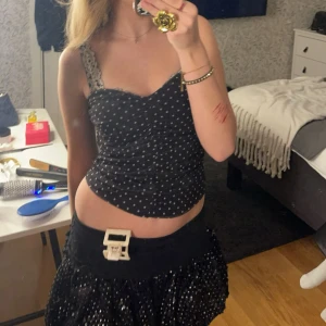 Svart prickig tubtopp - Säljer en svart tubtopp med vita prickar. Toppen har en figurnära passform och är perfekt för dig som gillar trendiga och söta plagg