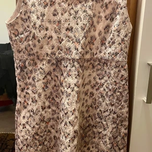 *NY*Blommig ärmlös klänning från Cream i stl 42  - Oanvänd. Säljer en ljus, ärmlös klänning från Cream med blommigt mönster och dragkedja i ryggen. Klänningen är tillverkad i bomull och polyester i lite tjockare tyg med en elegant, figurnära passform. Perfekt för vår och sommar! Naturvit med ljuslila/svarta/grå/roströda detaljer, tyget har vackra mönster. Normal i storlek. Fin kvalitet. 