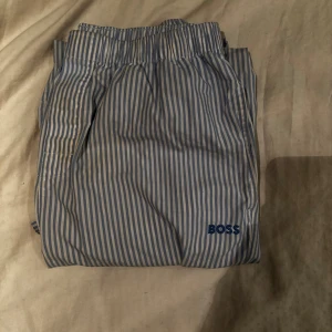 Pyjamas byxor Hugo Boss - Randiga vit och ljusblåa Hugo Boss pyjamas byxor som också kan användas som mjukisbyxor. Mycket bra skick och storlek M. Om ni har frågor är det bara att kontakta mig :)