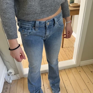 True Religion modell Joey, low waist flare - Säljer ett par ljusblåa jeans från True Religion med snygga detaljer på bakfickorna och silverfärgad knapp. Andvänd en gång pga för stora!😊💞Pris kan diskuteras!