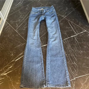 Blå bootcut jeans med broderade bakfickor - Säljer ett par klassiska blå bootcut jeans med snygga broderade detaljer på bakfickorna. Jeansen har normal passform och är tillverkade i denim.  Innermått 83(se bil) midjemått tvärs över 35( se bild)