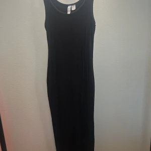 Svart ribbad långklänning från H&M - Säljer en svart ribbad långklänning från H&M. Klänningen är ärmlös med rund halsringning och har en tight passform. Perfekt för en stilren och enkel look.